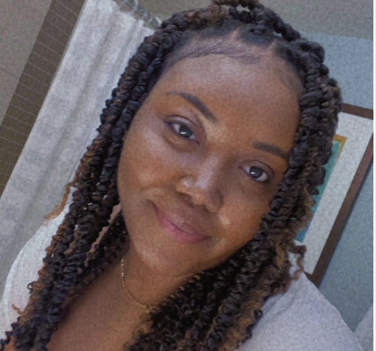 An african american woman smiling into the camera with black and light brown braids.